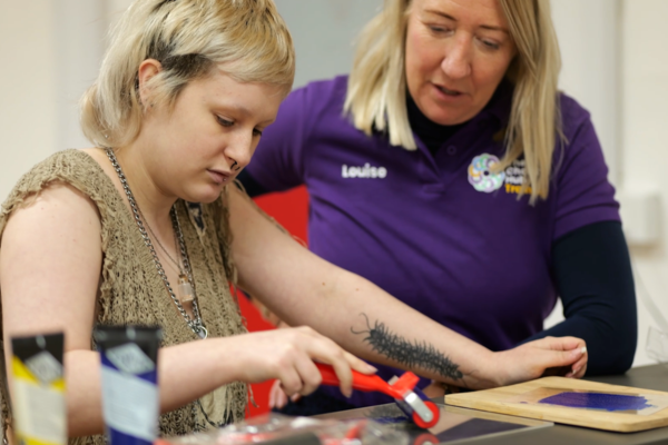 Student being supported by adult on a craft project